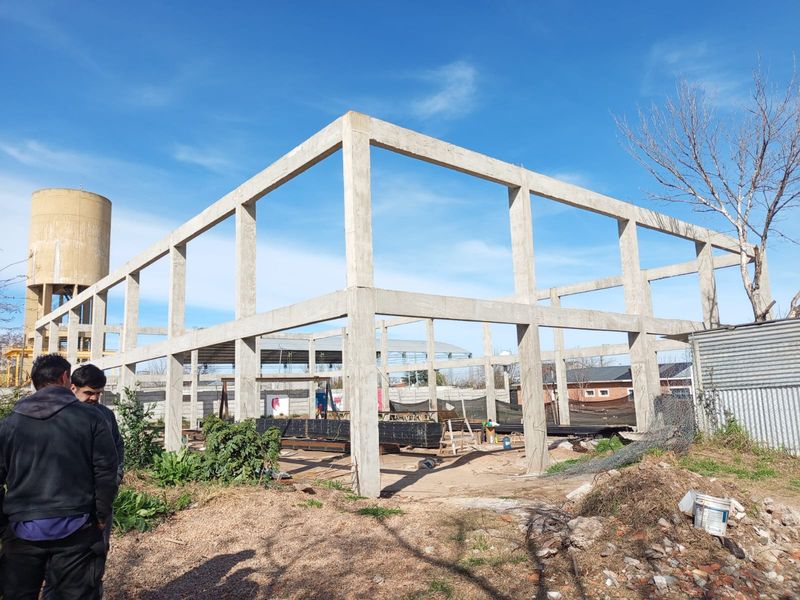 Pórticos de hormigón premoldeado montados en obra, con dos operarios al pie