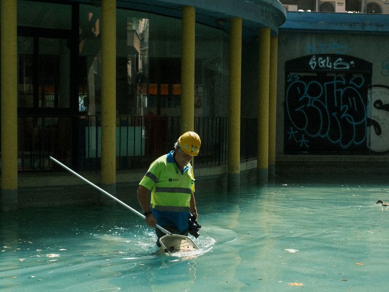 Operario podando un muro verde con una pértiga